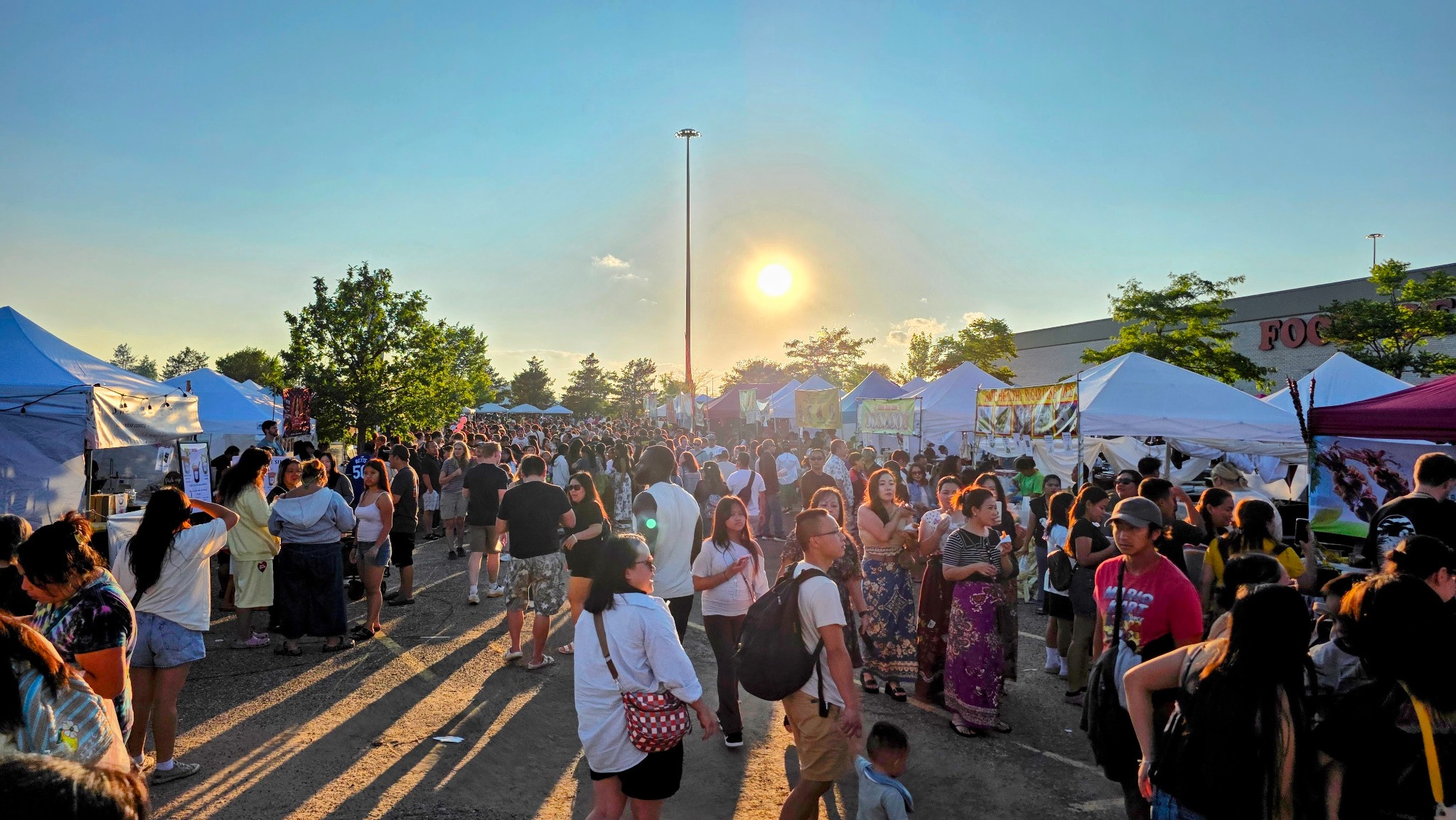 Crowds exploring food vendors at Asian Street Food Night Market at sunset